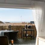 Terrasse mit Tisch, Stühlen und Grill. Blick aufs Meer und Grasland.