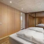 Schlafzimmer mit Holzwand und Spiegeltür. Bett mit weißen Kissen.