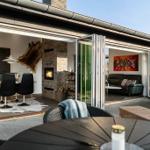 Terrasse mit Sitzgelegenheiten, die zum Innenraum mit Kamin und Essbereich führt.