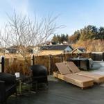 Terrasse mit Liegen, Sitzgelegenheiten und Blick auf Wohngebiet und Wald.