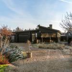 Moderne Villa mit Garage und Gartenweg. Holzverkleidung und großzügige Fenster.