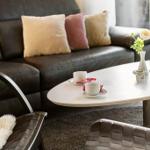Ein Wohnzimmer mit einem dunklen Sofa, einem weißen Tisch und zwei Stühlen.