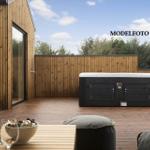 Terrasse mit Whirlpool, Holzwand und Sauna. Tisch mit Flasche und Gläsern.