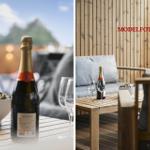 Auf der Terrasse steht ein Tisch mit einer Champagnerflasche, Gläsern und einer Schale mit Schokolade.