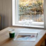 Ein Tisch mit Tasse und Zeitschrift vor einem Fenster mit Blick auf einen gefrorenen See.