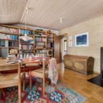 Dining room with wooden table, chairs, bookshelf, and wood stove.