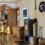 A room with a wood stove, bookcase, and hardwood floor. A picture hangs on the wall.