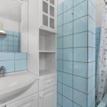 Bathroom with blue tiles, sink, mirror cabinet, and shower with curtain.