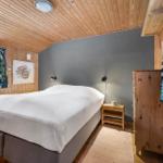 Bedroom with wooden walls, bed, nightstand, and windows.