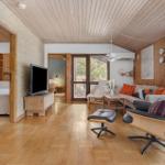 Living room with sofa, chair, and TV. Wooden ceiling and floor. Doors to bedroom and terrace.