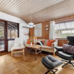 Living room with wooden ceiling, sofa, armchair, and terrace door.