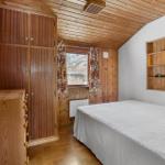 Bedroom with wooden floor, bed, wardrobe, and window with curtains.