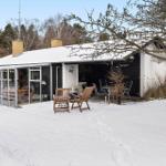 House with snow-covered roof, terrace, and garden furniture in winter.