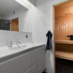 Bathroom with sink and integrated sauna with wooden bench and walls.