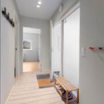 Hallway with wooden floor, shoe rack, and hooks on the walls.
