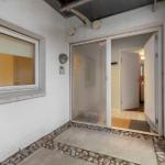 Entrance with glass door and window. White walls and stone path.