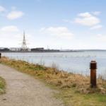 Path by the water with view of a ship and dog signs.