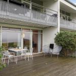 Deck with table, chairs, and chairs. Background: balcony with mesh and windows.