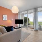 Living room with sofa, TV, and view of terrace and green area.
