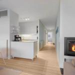 Living area with fireplace, kitchen, and dining area with wooden floor and modern furnishings.