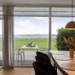 Dining room with view of lawn and water. Table, chairs, and pendant lamp visible.