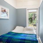 Bedroom with bed, blanket, and door to outdoor area.