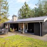 A dark wooden house with terrace, grill, and garden. Surrounded by trees.