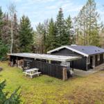 Wooden house with terrace, grill, and picnic table in the forest.
