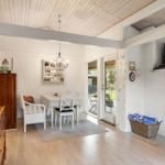 Living and dining area with fireplace, table and chairs, wooden floor and glass door to terrace.