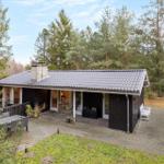 A house with terrace, grill and garden surrounded by trees.