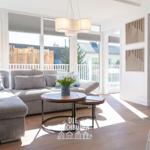 Wohnzimmer mit Sofa, Tisch und Fenstern zur Terrasse.