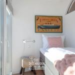 Schlafzimmer mit Bett, Kissen und Wandbild. Durchgang zur Terrasse mit Holzgeländer.