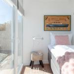 Schlafzimmer mit Bett, Wandbild und Glasfront zum Balkon.