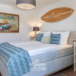 Schlafzimmer mit Bett, Nachttisch und Wanddekoration.