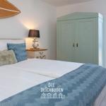 Schlafzimmer mit Bett, Kleiderschrank und Fenster. Wanddekoration und Nachttisch sind sichtbar.