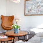 Ein Wohnzimmer mit brauner Ledersessel, Holztisch und Wandbild.