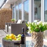 Terrasse mit Sitzgruppe, Blumen und Obsttablett.