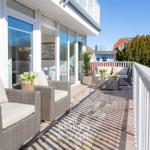Terrasse mit Rattanmöbeln, Blumen und Blick auf Wohnbereich.