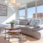 Wohnzimmer mit Sofa, Tisch und Blick auf Balkon.