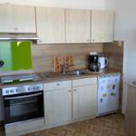 Küche mit Holzschränken, Herd, Spüle und Kühlschrank.