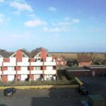 Rotes Wohnhaus mit Balkonen und Parkplatz im Vordergrund.