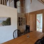 Esszimmer mit Holztisch, Stühlen und Wandbild. Holzwände und Dachschräge.