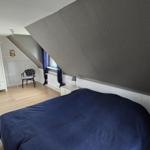 Schlafzimmer mit Dachschrägen, Bett, Kleiderschrank und Stuhl.