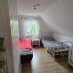 Zwei Betten in einem Dachzimmer mit Fenster und Bücherregal.