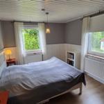 Schlafzimmer mit Bett, zwei Fenstern und Nachttischen.