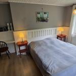 Schlafzimmer mit Bett, Nachttischen und Fenster mit Blick auf Garten.