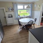 Küche mit Esstisch, Fenster und Blick auf Grünfläche.