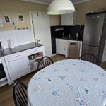 Küche mit Esstisch, Kühlschrank und Herd. Tischdecke mit Blumenmuster.