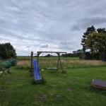 Hinterhof mit Spielplatz, Schaukel und Rutsche auf grünem Rasen.