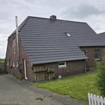 Haus mit Ziegeldach, Garten und gepflastertem Hof. 